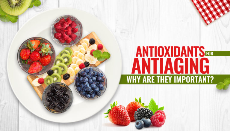 A top view of assorted fresh fruits—strawberries, raspberries, blueberries, blackberries, kiwi, and banana—arranged on a board with the text: Antioxidants for Antiaging: Why are they important?.