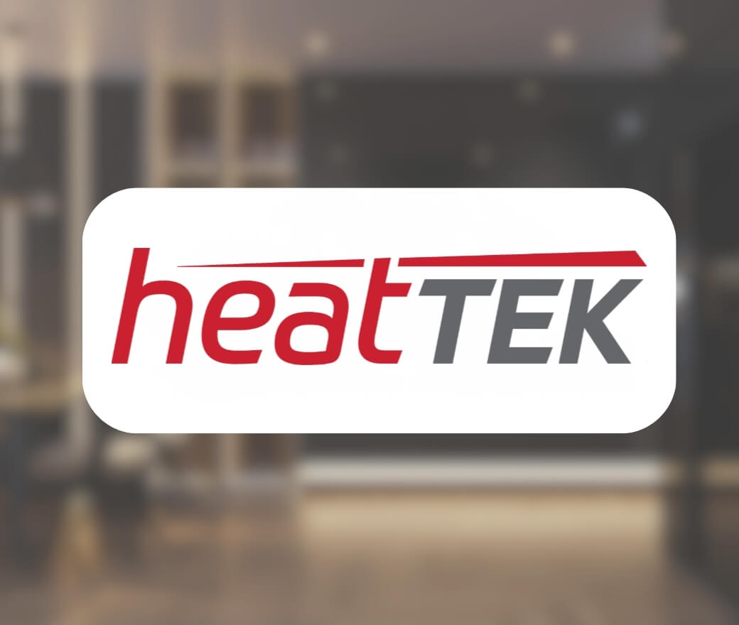The image shows the logo heatTEK with heat in red and TEK in gray, both in bold, modern font, over a blurred background of an indoor space.